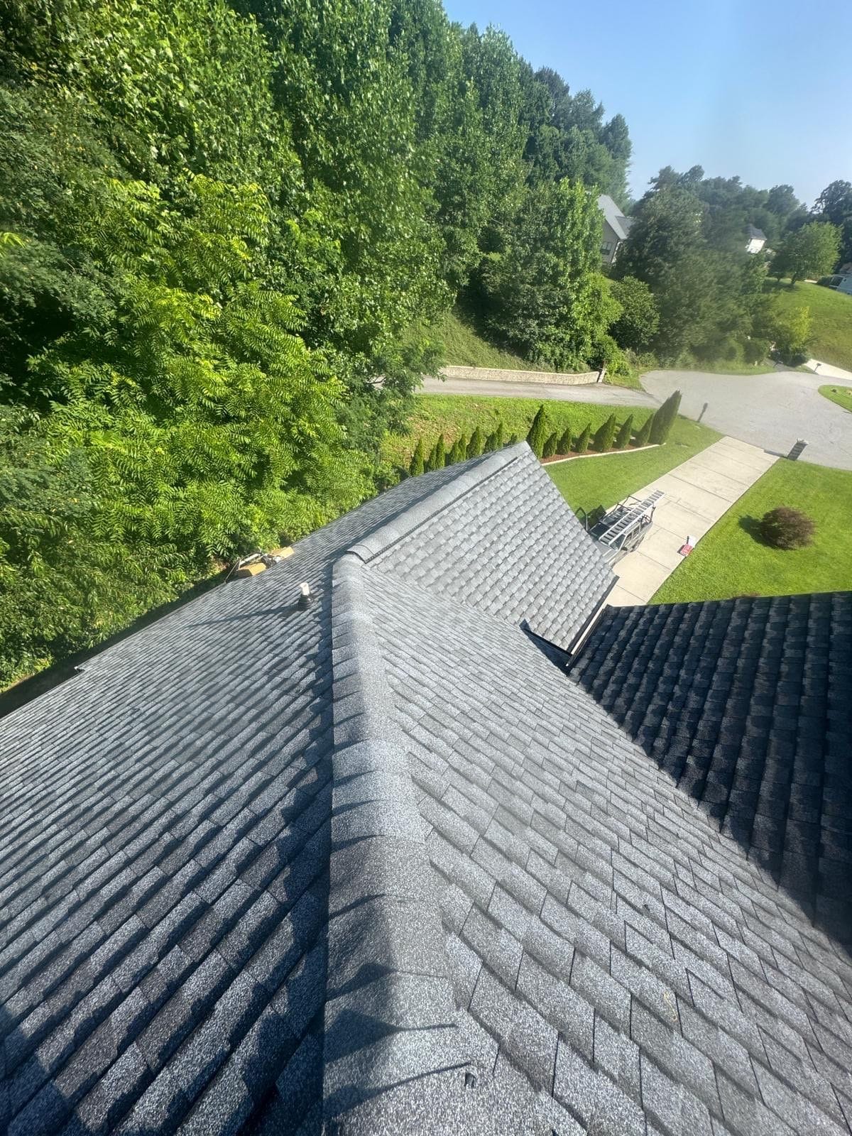 Freshly installed gray shingle roof overlooking a green hillside neighborhood