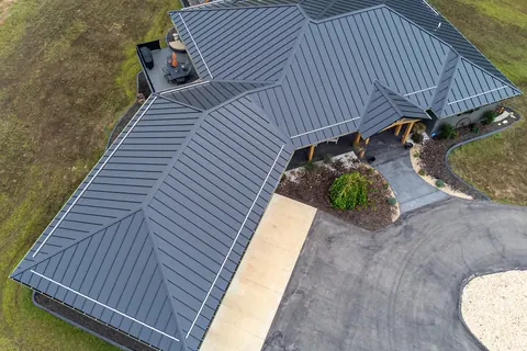 A home with a dark gray standing-seam metal roof, seen from above