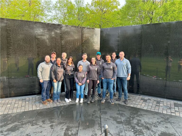The Panda Exteriors team in front of a black granite memorial wall