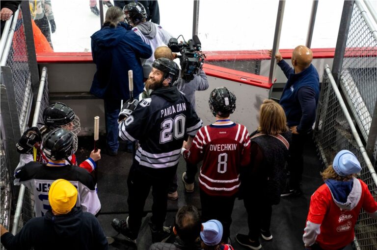 Hockey players in Panda jerseys heading out to the ice past young fans